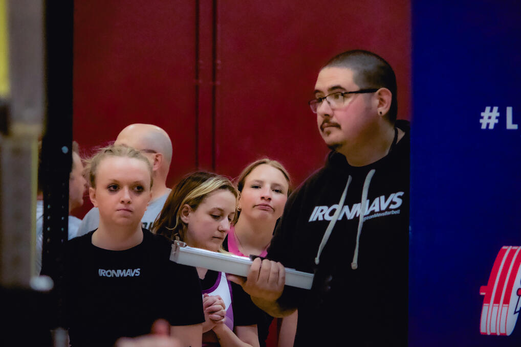 Coach Trujillo and athletes watching a lift intently from the warm-up area