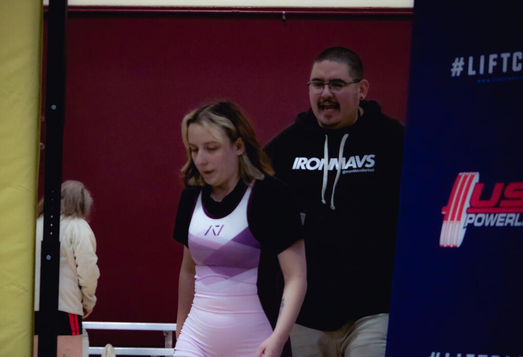 Coach Trujillo walking an athlete to the platform at a competition