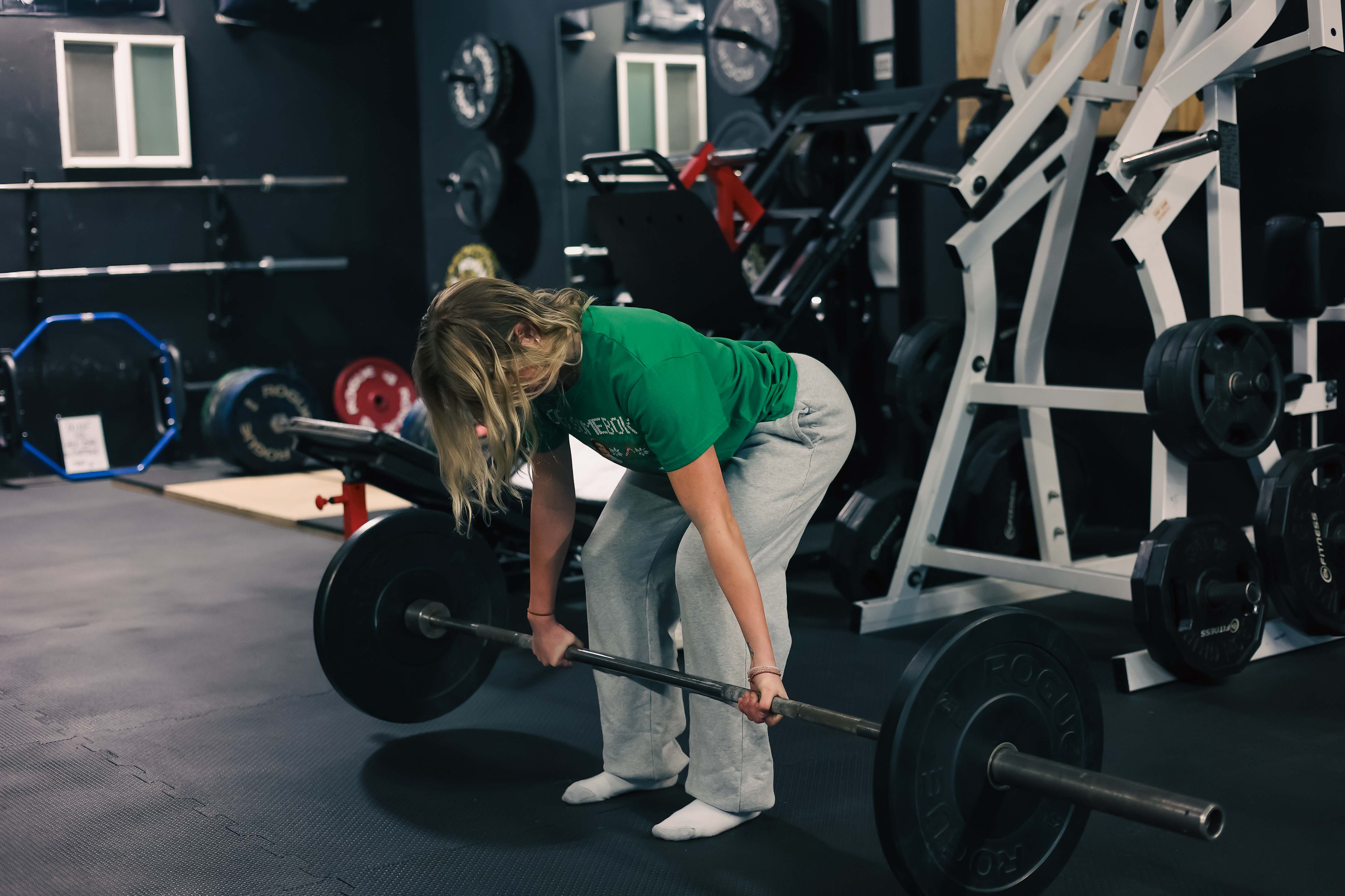 A lifter training with a loaded barbell inside the Top Set training facility surrounded by racks and plates