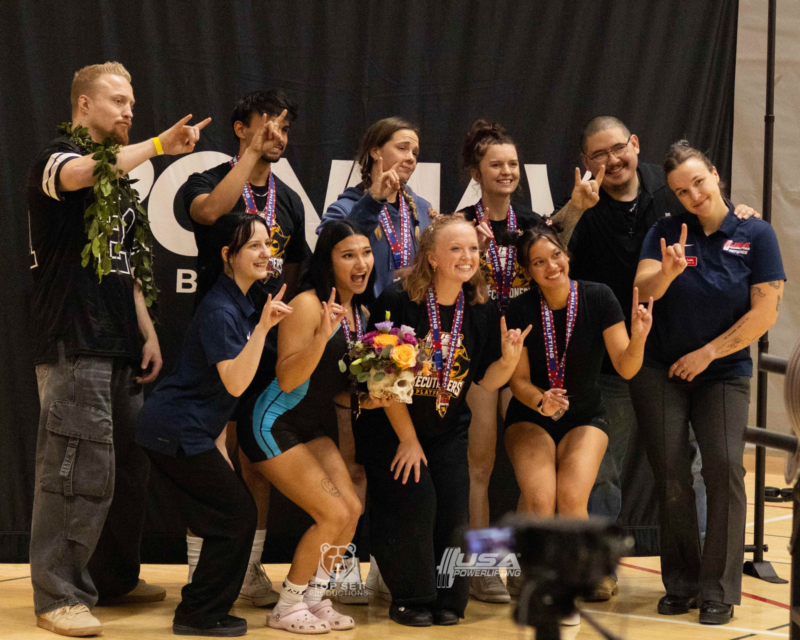 Top Set athletes, coaches, and referee celebrating with their medals at the Executioners Platform USA Powerlifting meet